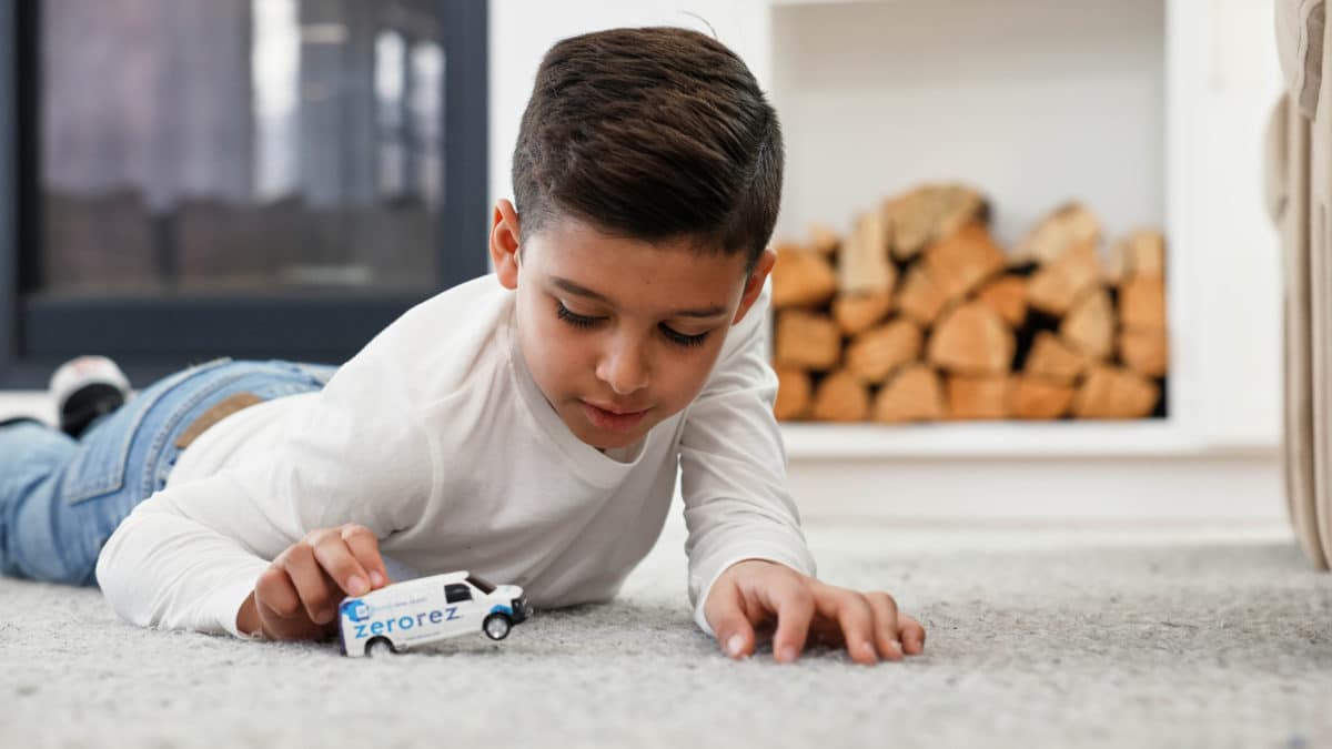kid playing with a zerorez truck on the carpet
